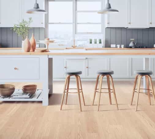Kitchen island with chairs on wood flooring.